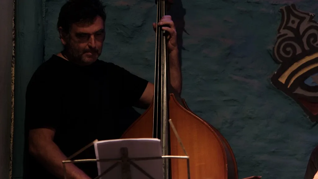 Musician playing double bass on stage with a music stand.
