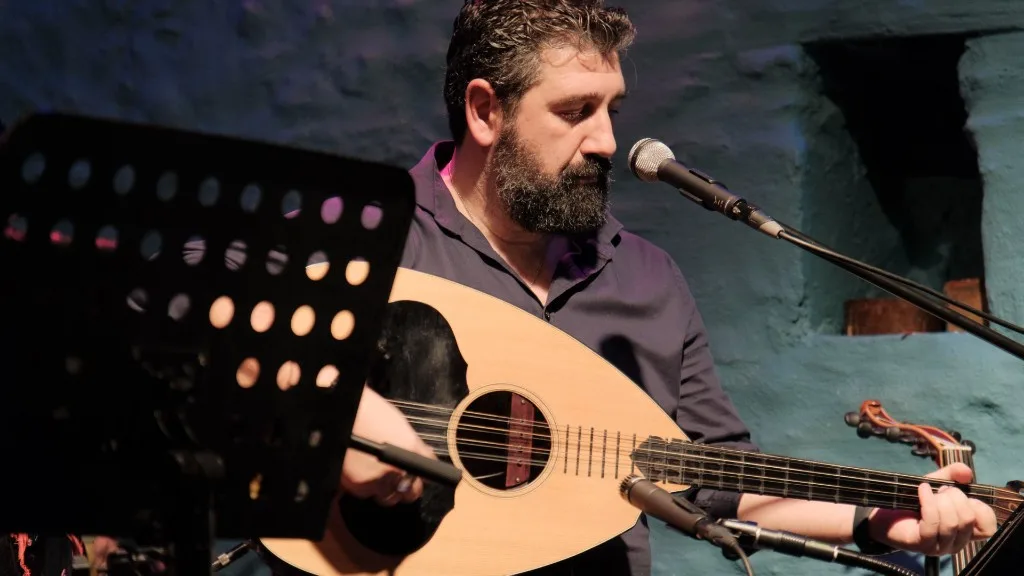 Close-up of a musician with laouto in front of a microphone.