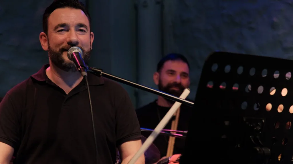Musician with Cretan lyra singing at the microphone.