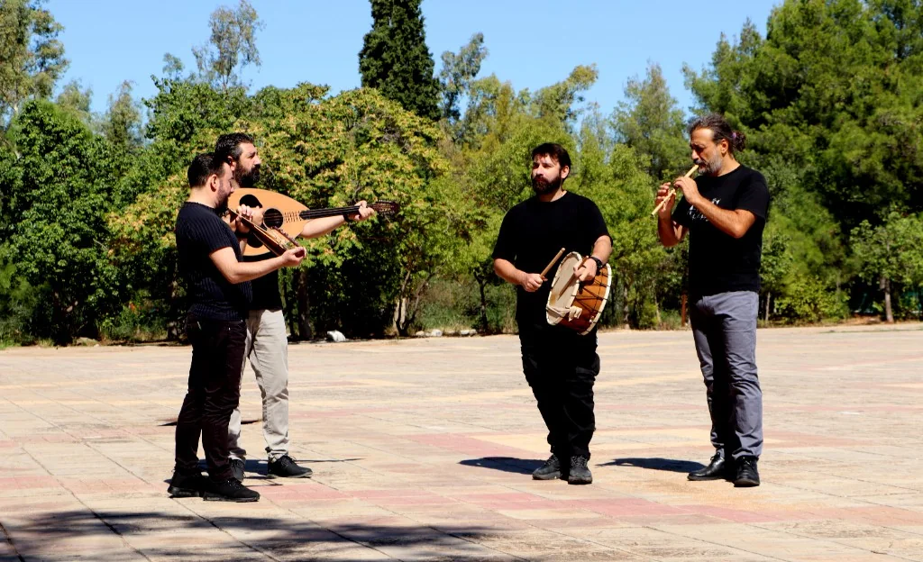 Esmiya outdoors: four musicians with traditional instruments.