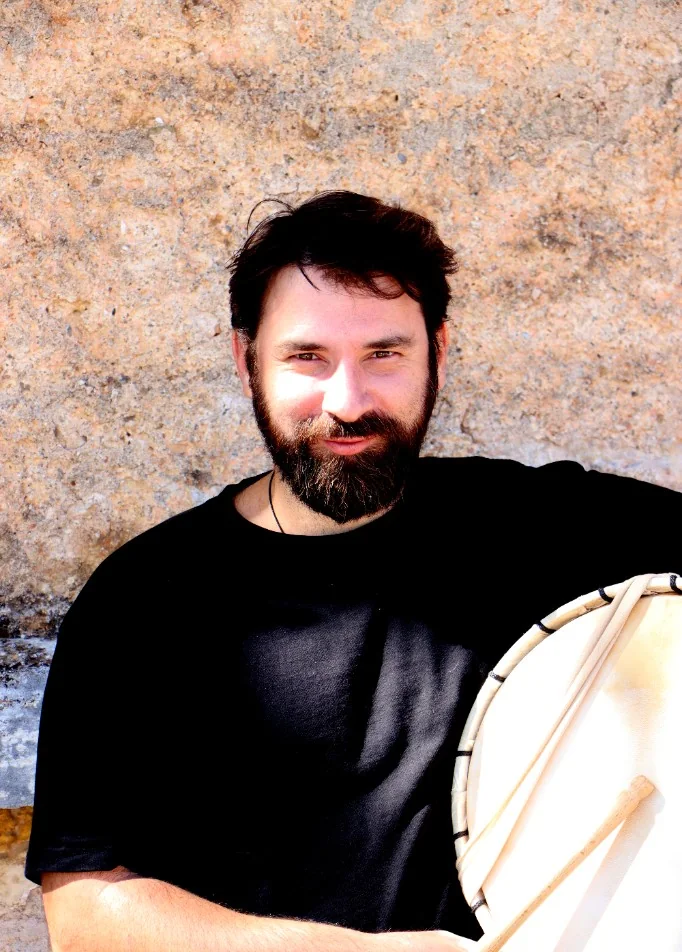 Musician with a frame drum and wooden beaters.